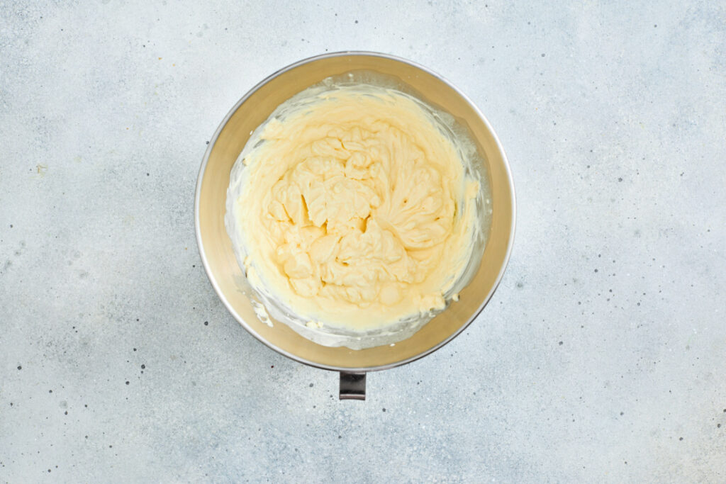 A mixing bowl filled with whipped buttercream sits on a light gray countertop, perfect for topping your St. Patrick’s Day Green Jello Parfaits.